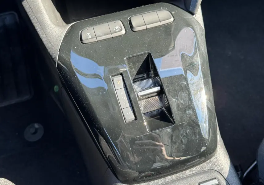 Vue rapprochée de la console centrale noire brillante de l’Opel Corsa 2025 avec sélecteur de boîte automatique et boutons de contrôle.