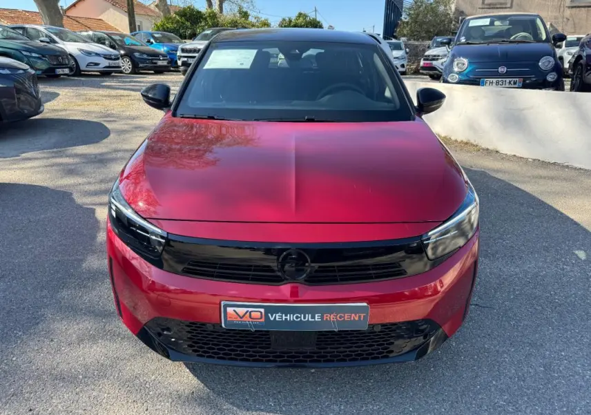 Opel Corsa rouge vue de face, mettant en valeur sa calandre noire brillante et ses phares fins modernes.