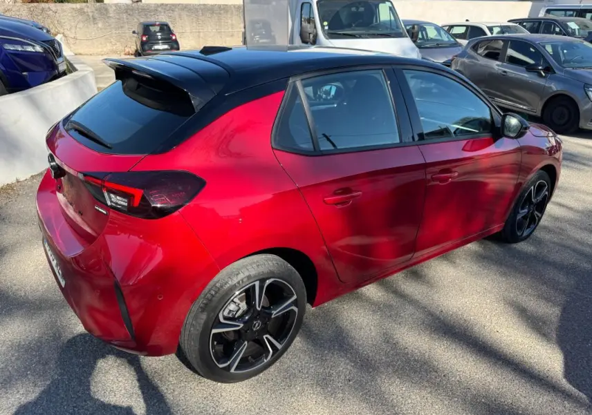 Vue 3/4 arrière droite d'une Opel Corsa rouge 2025 avec toit noir, jantes alliage 17 pouces et feux arrière LED.