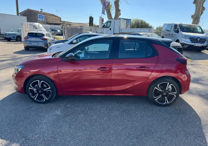 Opel Corsa rouge vue de profil côté gauche, avec jantes alliage noires et toit noir contrasté.