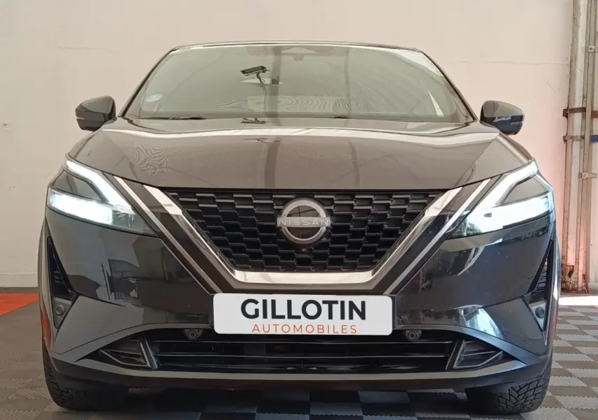 Vue avant du Nissan Qashqai noir 2023 avec phares LED allumés et calandre chromée distinctive.