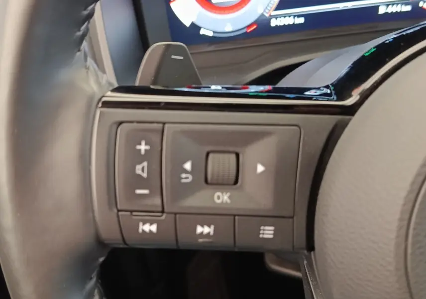 Gros plan sur les commandes au volant du Nissan Qashqai Tekna 2023, avec affichage numérique en arrière-plan.