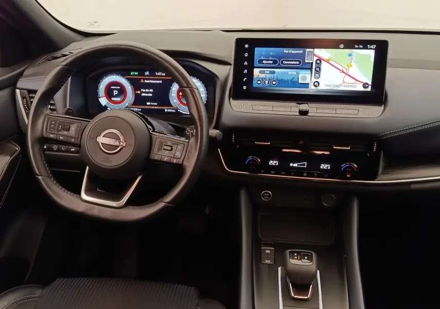 Vue intérieure du tableau de bord noir du Nissan Qashqai 2023 avec écran tactile 12,3 pouces et volant cuir multifonctions.