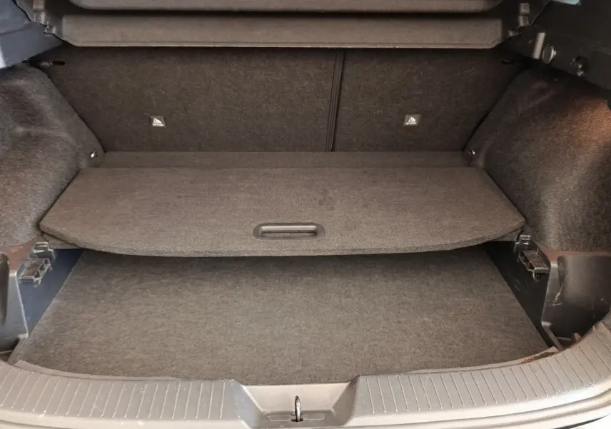Coffre ouvert du Nissan Qashqai noir 2023, vue de l'intérieur montrant la tablette de séparation et le revêtement gris.