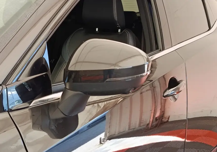 Rétroviseur côté conducteur noir brillant sur Nissan Qashqai 2023, vue rapprochée du côté gauche avec porte et poignée visibles.