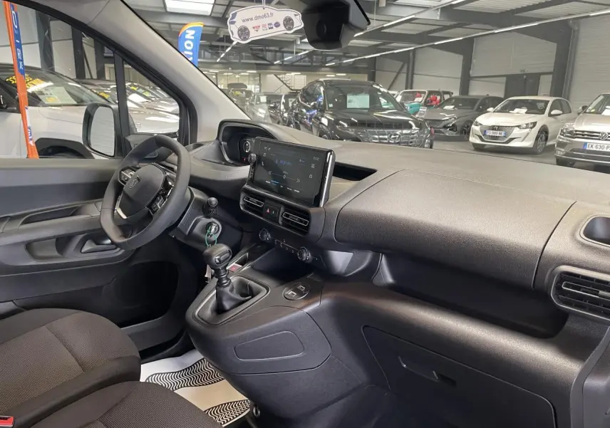 Vue intérieure côté conducteur du Peugeot Partner 2026, montrant tableau de bord noir avec écran tactile central et boîte manuelle.