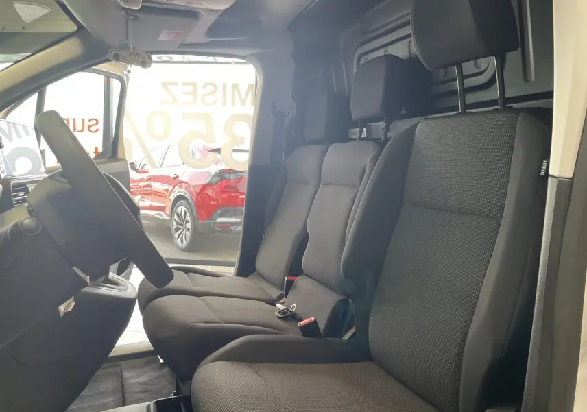 Vue intérieure côté conducteur du Peugeot Partner blanc, montrant la banquette passager 2 places en tissu noir avec appuis-tête.