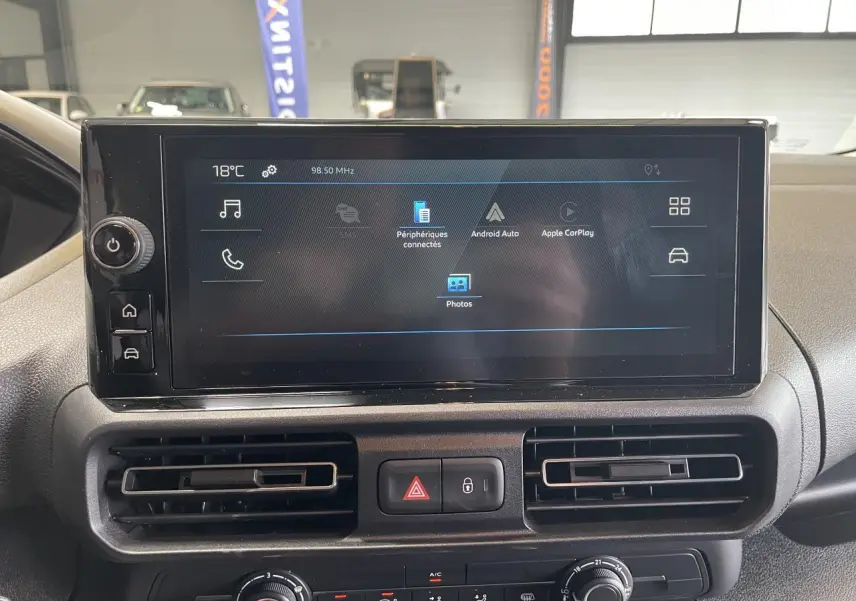 Écran tactile central du tableau de bord du Peugeot Partner blanc, avec commandes climatisation et ventilation visibles.