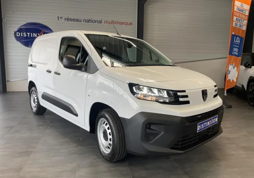 Vue 3/4 avant droit du fourgon blanc Peugeot Partner 2026 avec pare-chocs noirs et jantes tôles grises en showroom.