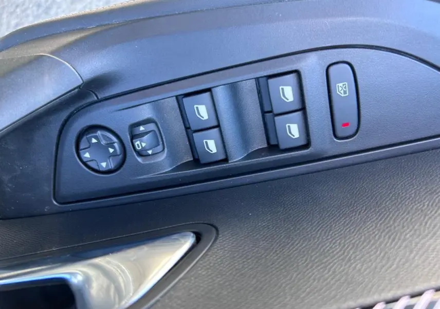 Gros plan sur les commandes électriques des vitres et rétroviseurs côté conducteur du Peugeot 2008 Hybrid noir 2025.