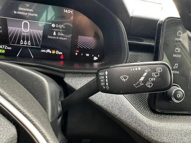 Gros plan sur la commande d’essuie-glace à gauche du volant dans l’habitacle noir du Skoda Scala blanc cristal.