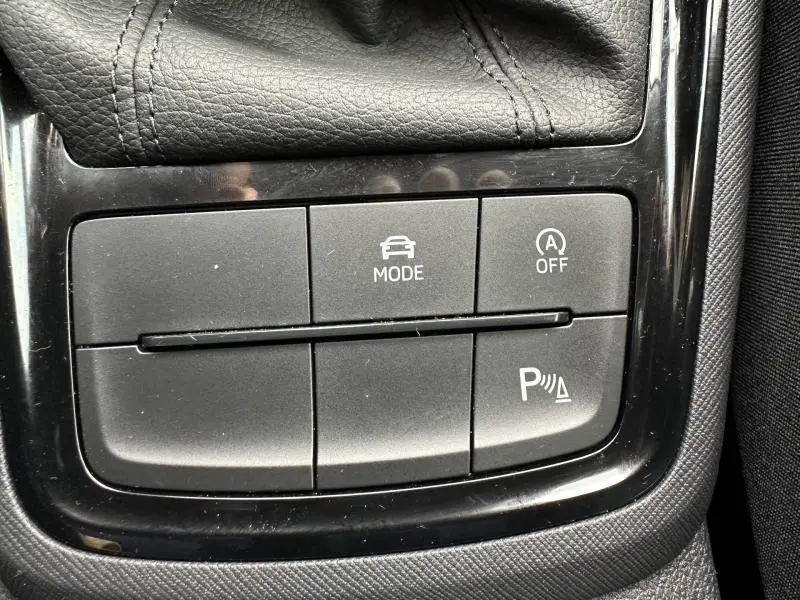 Gros plan sur les boutons de commande du mode de conduite, arrêt auto et aide au stationnement dans une Skoda Scala blanche.