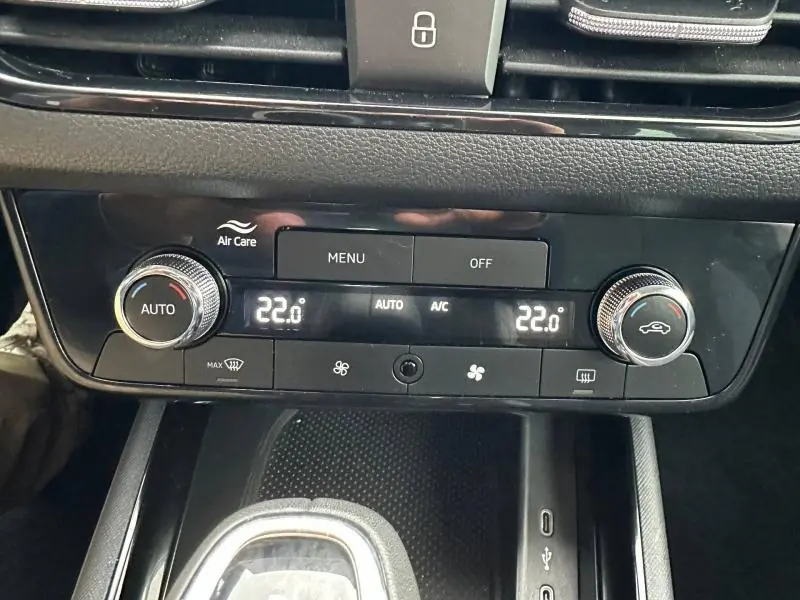 Gros plan sur la console centrale noire du Skoda Scala blanc, affichant la climatisation automatique à 22°C.