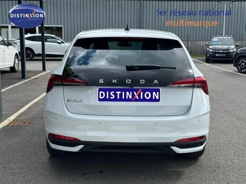 Vue arrière d'une Skoda Scala blanc cristal avec feux arrière LED et vitrage arrière teinté sur parking.