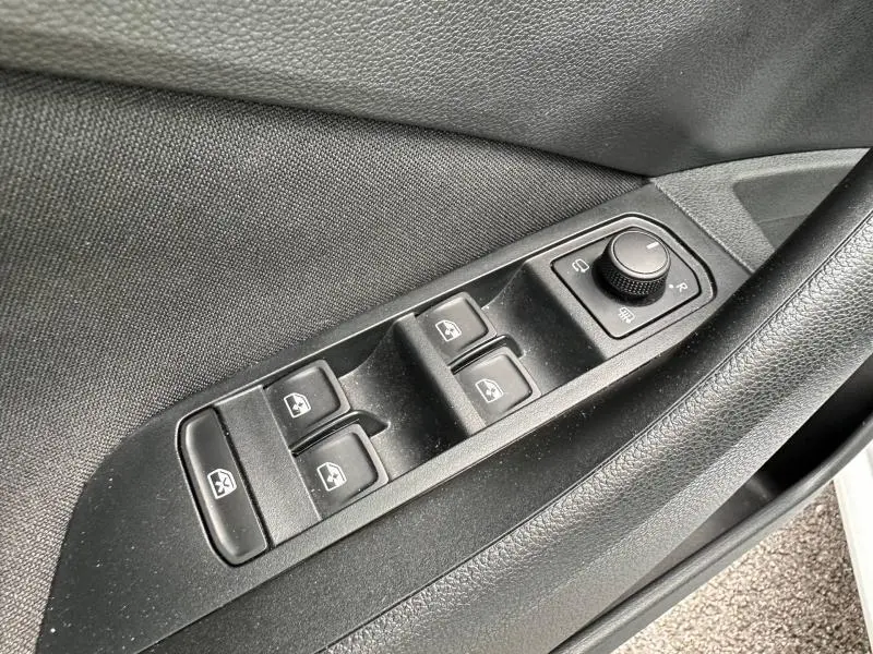 Vue rapprochée des commandes de lève-vitres et réglage des rétroviseurs côté conducteur d'une Skoda Scala blanche.