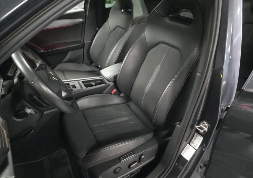 Vue intérieure côté conducteur du CUPRA Leon Sportstourer gris, mettant en valeur le siège baquet noir avec surpiqûres copper.