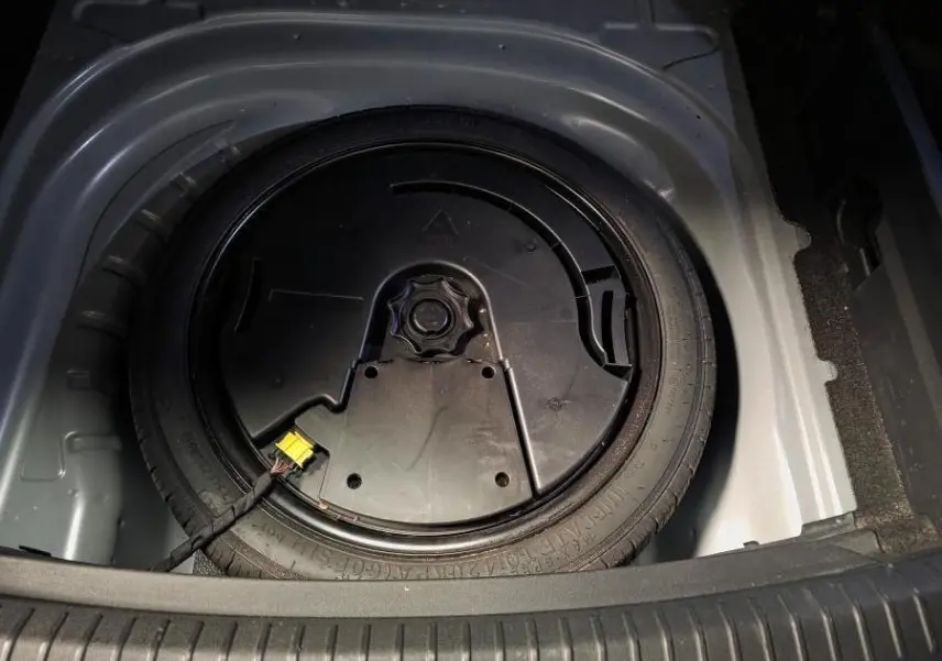 Vue plongeante sur la roue de secours dans le coffre du CUPRA Leon Sportstourer gris 2023, détail du rangement intérieur.