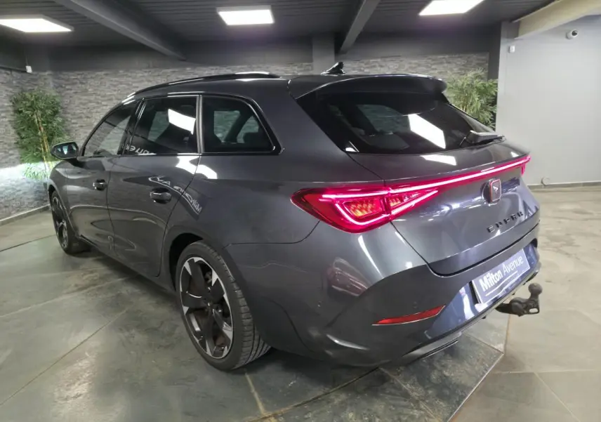 Vue 3/4 arrière droite d'une CUPRA Leon Sportstourer gris magnétique avec feux LED et crochet d'attelage escamotable.