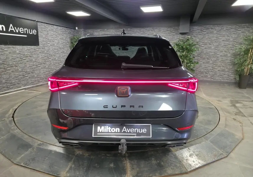 Vue arrière d'un CUPRA Leon Sportstourer gris avec feux LED en bandeau et crochet d'attelage escamotable visible.