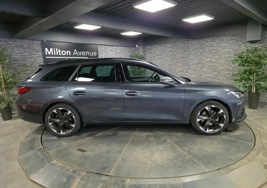 Profil droit d'une CUPRA Leon Sportstourer gris magnétique 2023 en intérieur avec jantes alliage 18 pouces.