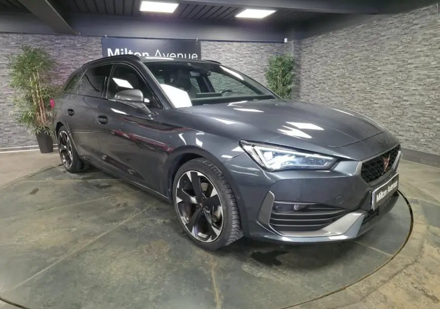 Vue 3/4 avant droite d'une CUPRA Leon Sportstourer gris métallisé avec jantes alliage noires et détails sportifs.