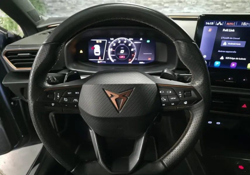 Vue rapprochée du volant cuir noir perforé avec logo CUPRA cuivre et combiné d'instruments digital couleur.