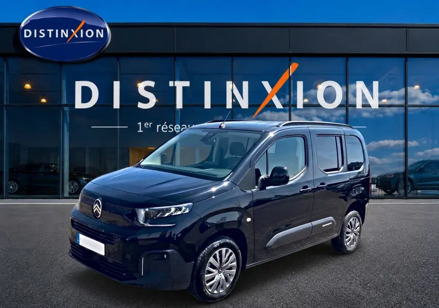 Citroën Berlingo noir vue 3/4 avant droit devant showroom Distinxion avec jantes alu et vitres teintées.