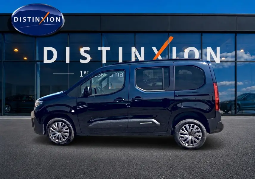 Profil droit du Citroën Berlingo noir 2026 avec barres de toit et jantes alu devant une vitrine Distinxion.