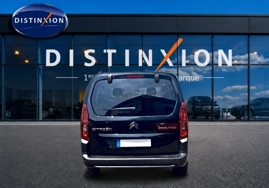 Vue arrière d’un Citroën Berlingo noir 2026 avec feux verticaux et hayon vitré devant un bâtiment vitré Distinxion.