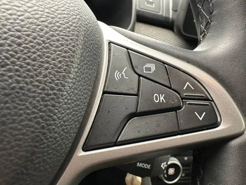 Gros plan sur les commandes multifonctions noires du volant du Dacia Jogger 2025, finition Expression, intérieur gris.