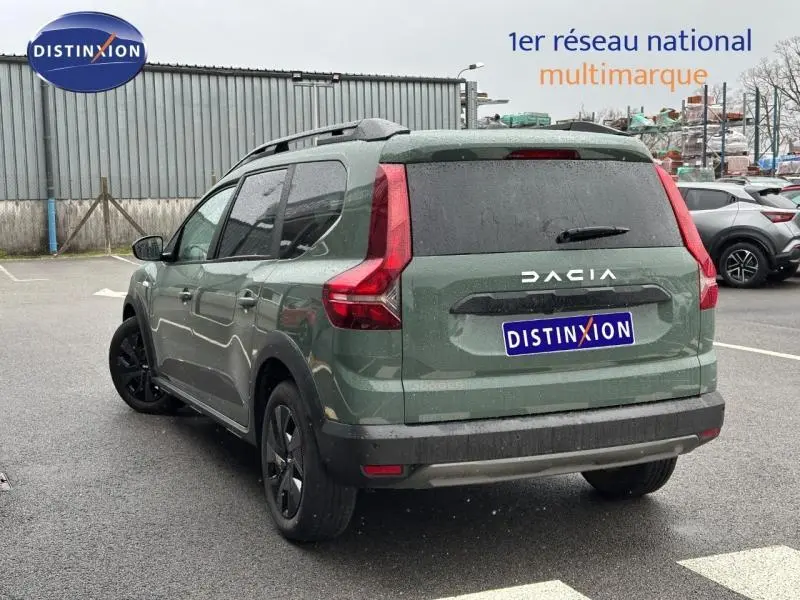 Vue 3/4 arrière d'un Dacia Jogger 2025 kaki lichen, version 7 places, avec feux arrière en forme de L et jantes noires.