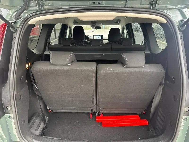 Vue arrière du coffre ouvert d'un Dacia Jogger 2025 kaki lichen, montrant les sièges arrière rabattus et l'intérieur spacieux.