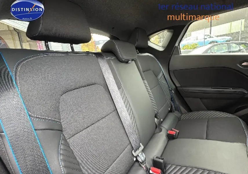 Vue intérieure montrant la banquette arrière noire avec surpiqûres bleues du Renault Captur 1.8 e-tech hybride 2025.