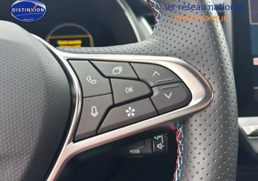 Gros plan sur le volant cuir perforé avec commandes multifonctions et surpiqûres tricolores du Renault Captur hybride 2025.