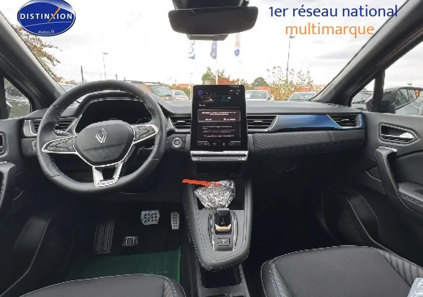 Vue intérieure avant du Renault Captur gris rafale, mettant en valeur le volant cuir multifonction et l'écran tactile vertical central.