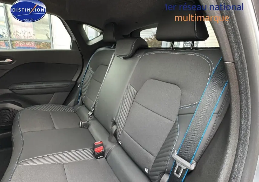 Vue intérieure de la banquette arrière du Renault Captur gris rafale, avec surpiqûres bleues et ceintures visibles.