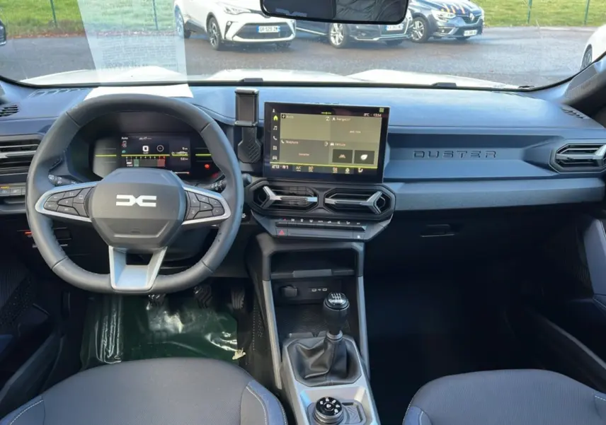 Vue intérieure avant du Dacia Duster 2026 noir nacré, montrant le volant cuir, la boîte manuelle et l'écran tactile central.