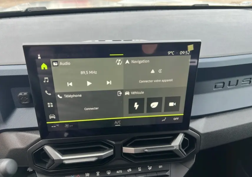 Vue rapprochée de l’écran tactile central et de la planche de bord gris foncé avec logo DUSTER embossé.