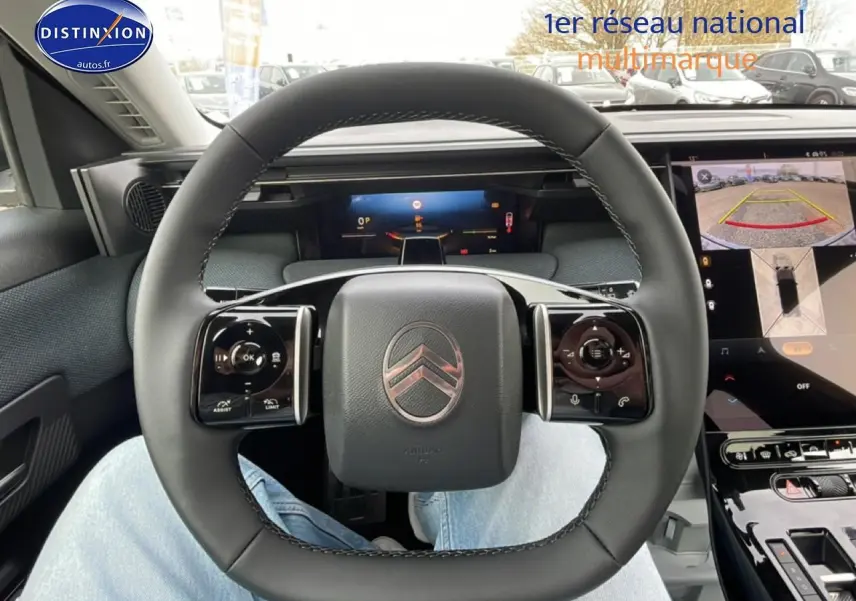 Vue intérieure centrée sur le volant noir du Citroën C5 Aircross 2026 avec écran tactile et caméra de recul affichée.