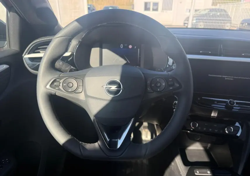 Vue intérieure centrée sur le volant noir de l'Opel Corsa 2025, avec tableau de bord et écran tactile visibles.