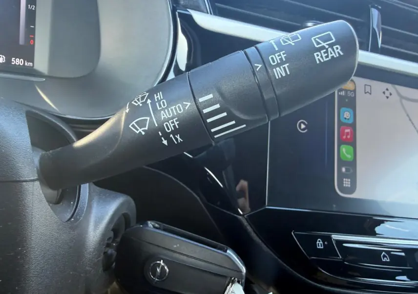 Gros plan sur la commande d’essuie-glace et l’écran tactile du tableau de bord d’une Opel Corsa rouge 2025.