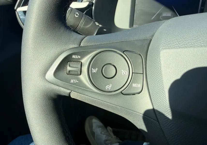 Gros plan sur les commandes de régulateur de vitesse au volant d'une Opel Corsa rouge 2025, version hybride essence.