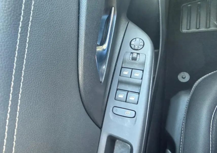 Gros plan sur la commande des vitres côté conducteur de l’Opel Corsa rouge 2025, avec surpiqûres blanches visibles.