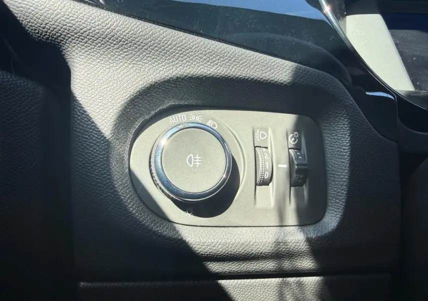 Gros plan sur la molette de réglage des phares dans l’habitacle noir de l’Opel Corsa rouge 2025.