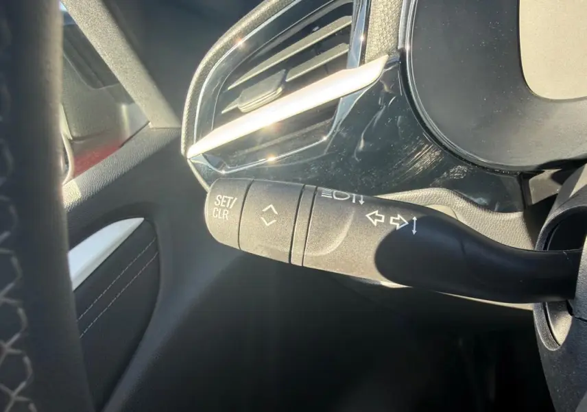 Détail du commodo de clignotant à gauche dans l’habitacle d’une Opel Corsa rouge 2025, version 1.2 Turbo Hybrid.