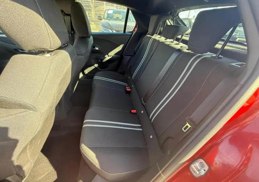 Vue intérieure arrière côté droit de l’Opel Corsa rouge 2025, montrant les sièges arrière avec bandes blanches.