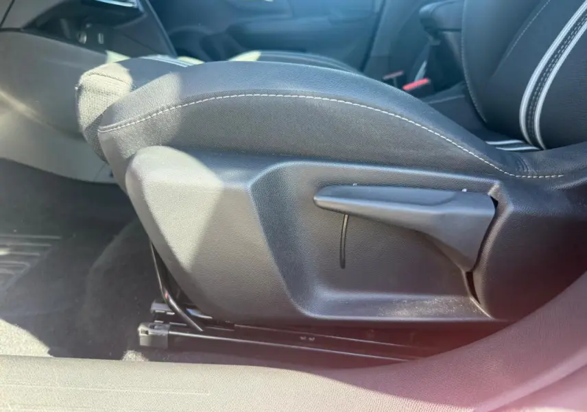 Détail du réglage manuel du siège avant côté conducteur d'une Opel Corsa rouge 2025, tissu noir.