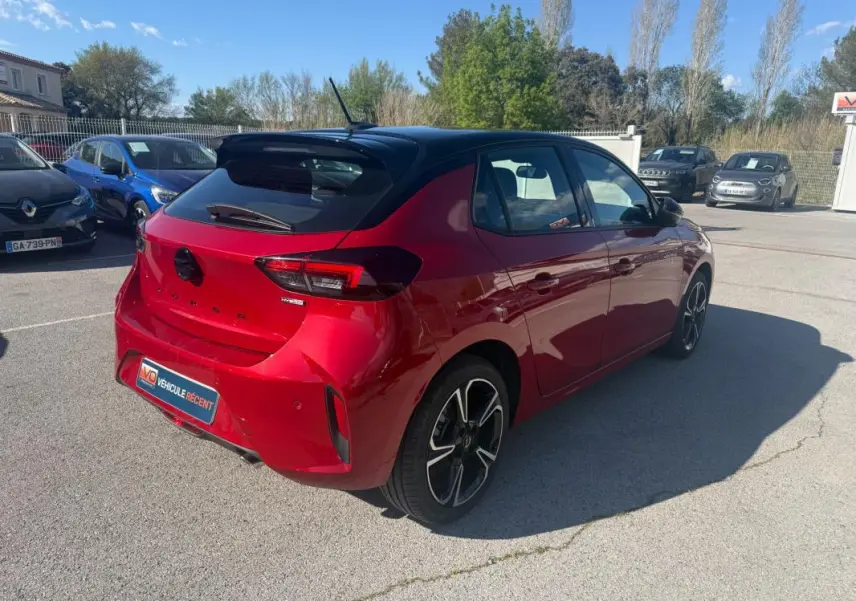 Vue 3/4 arrière droite de l'Opel Corsa rouge 2025 avec toit noir et jantes alliage distinctives.