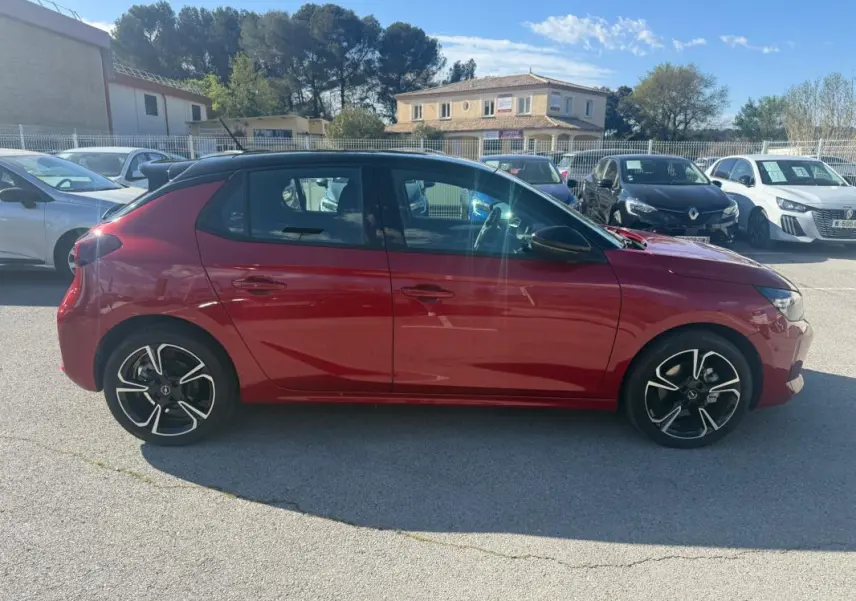 Opel Corsa rouge 2025 vue de profil côté gauche, avec jantes alliage noires et toit noir contrasté.