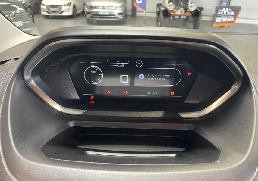 Vue rapprochée du tableau de bord numérique du Peugeot Partner blanc, affichant les alertes et compteurs digitaux.